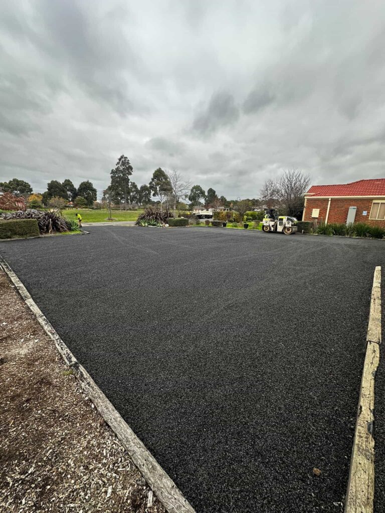 Freshly paved black asphalt driveway in a landscaped residential area